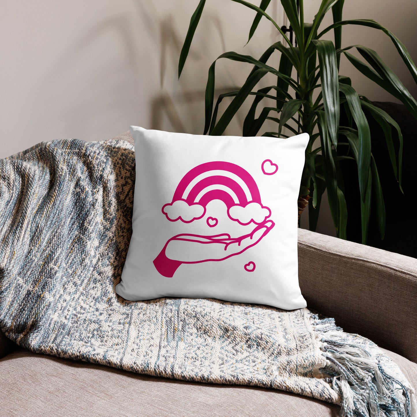 pillow with print of pink hand holding a pink rainbow