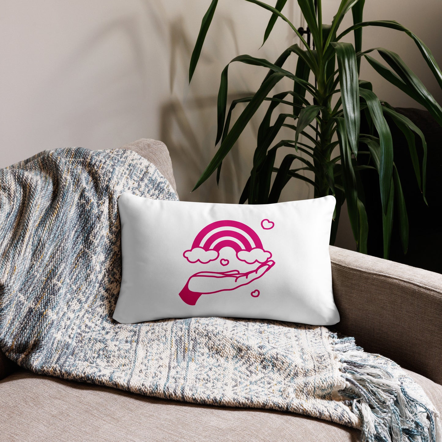pillow with print of pink hand holding a pink rainbow