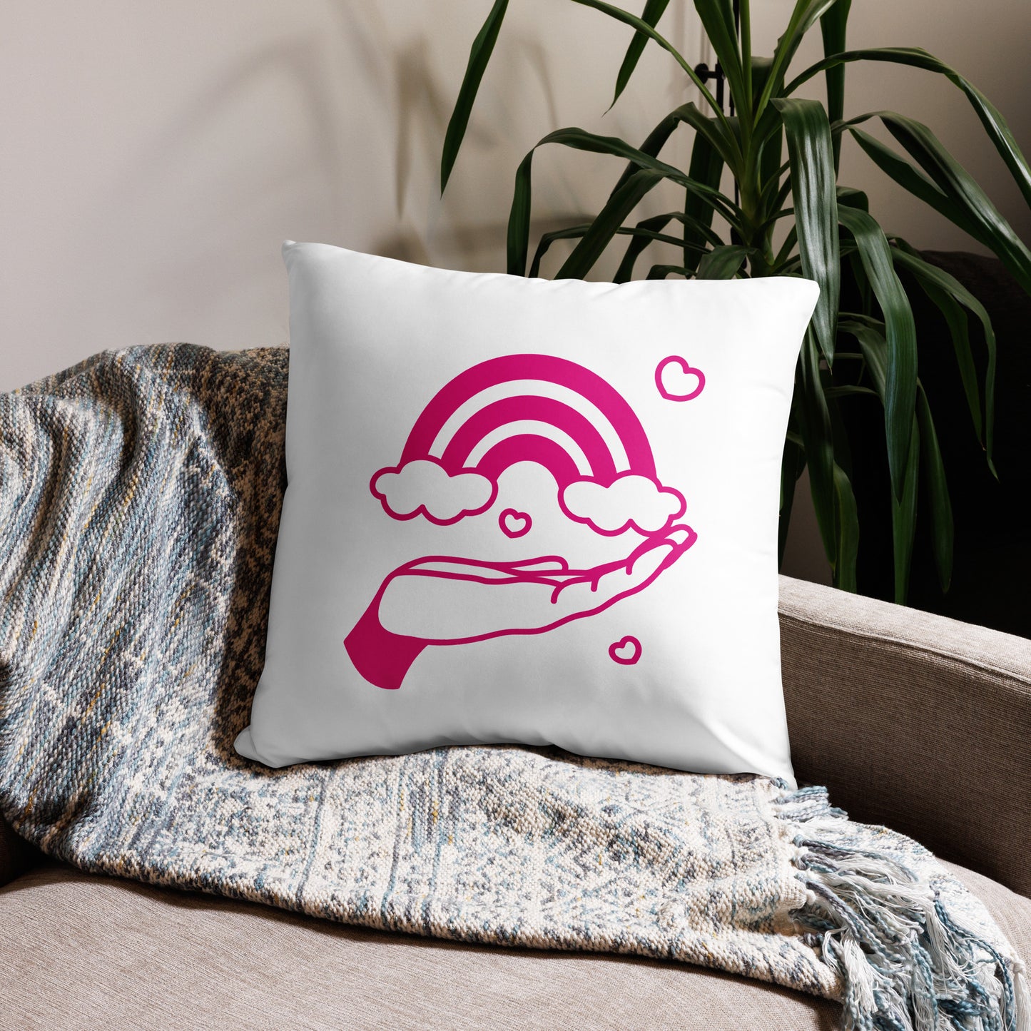 pillow with print of pink hand holding a pink rainbow