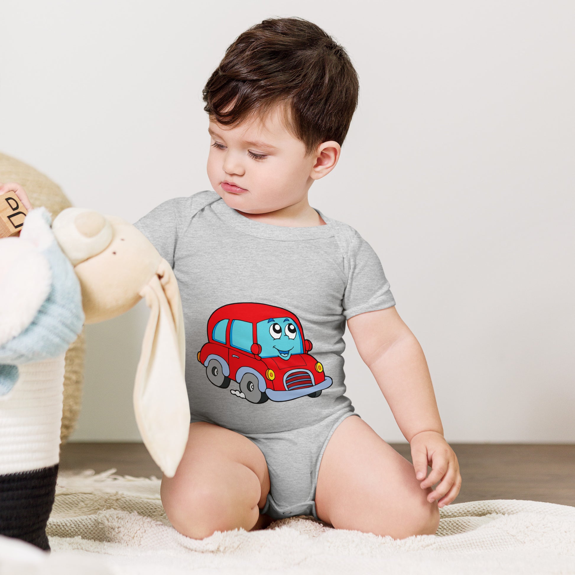 baby with grey short sleeve one piece with picture of a red car