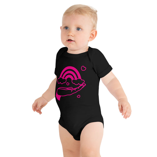 baby with black short sleeve one piece with print of pink hand holding a pink rainbow