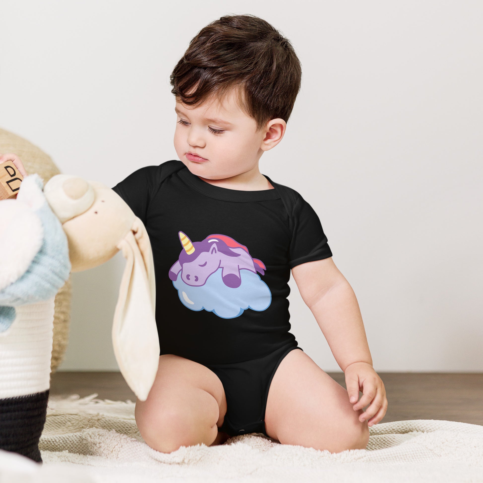 baby with a black bodysuit with a print of a sleeping unicorn on a cloud