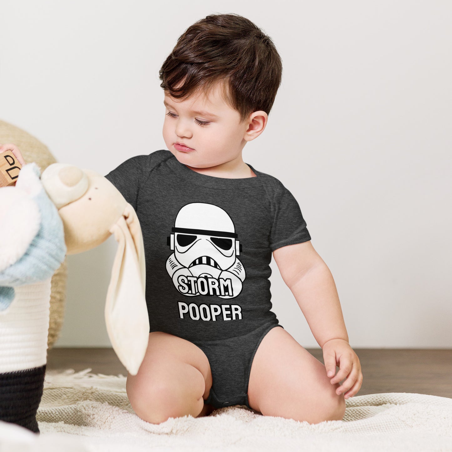 Baby with dark grey short sleeve one piece with picture of a Storm trooper with the text "StORM POOPER"