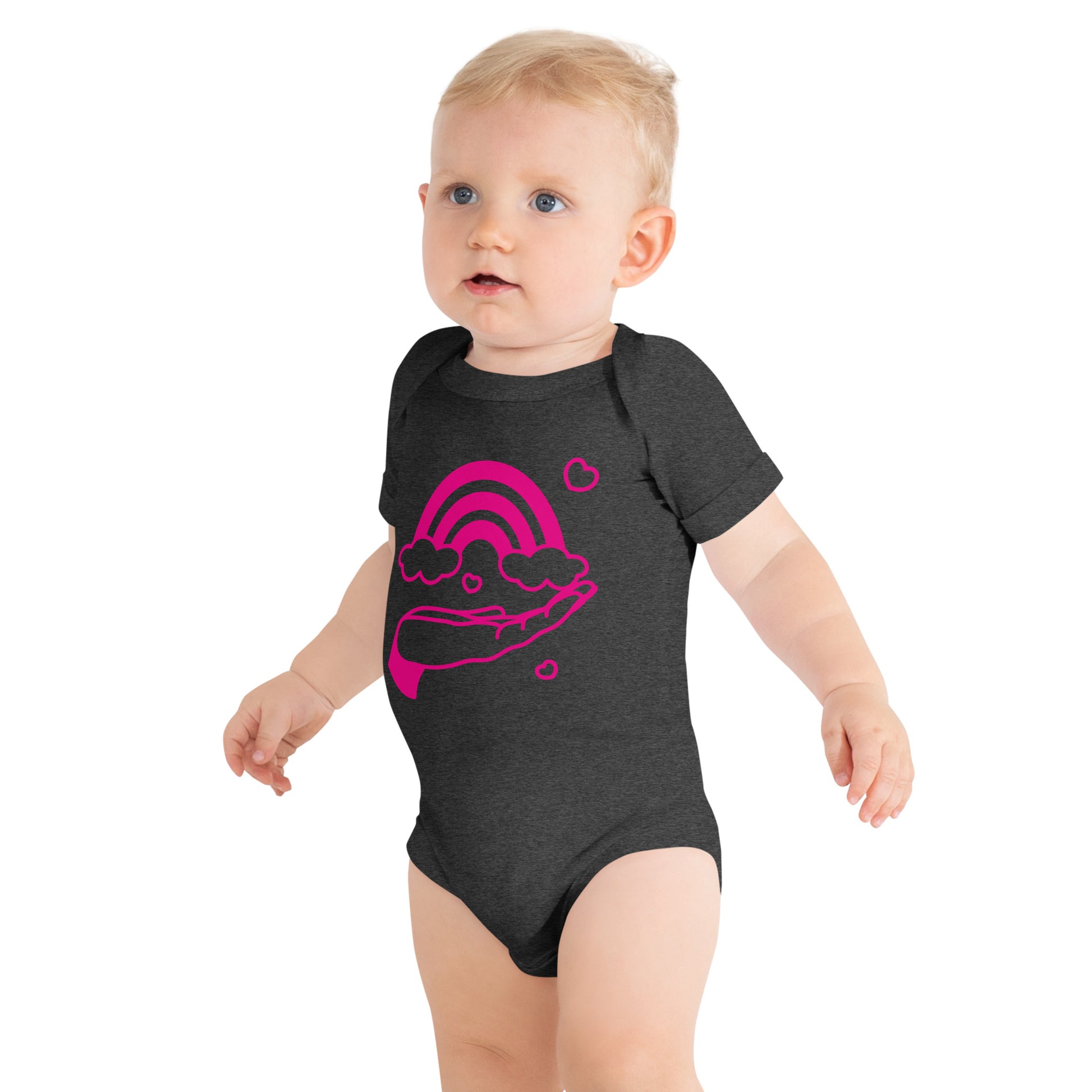 baby with dark grey short sleeve one piece with print of pink hand holding a pink rainbow