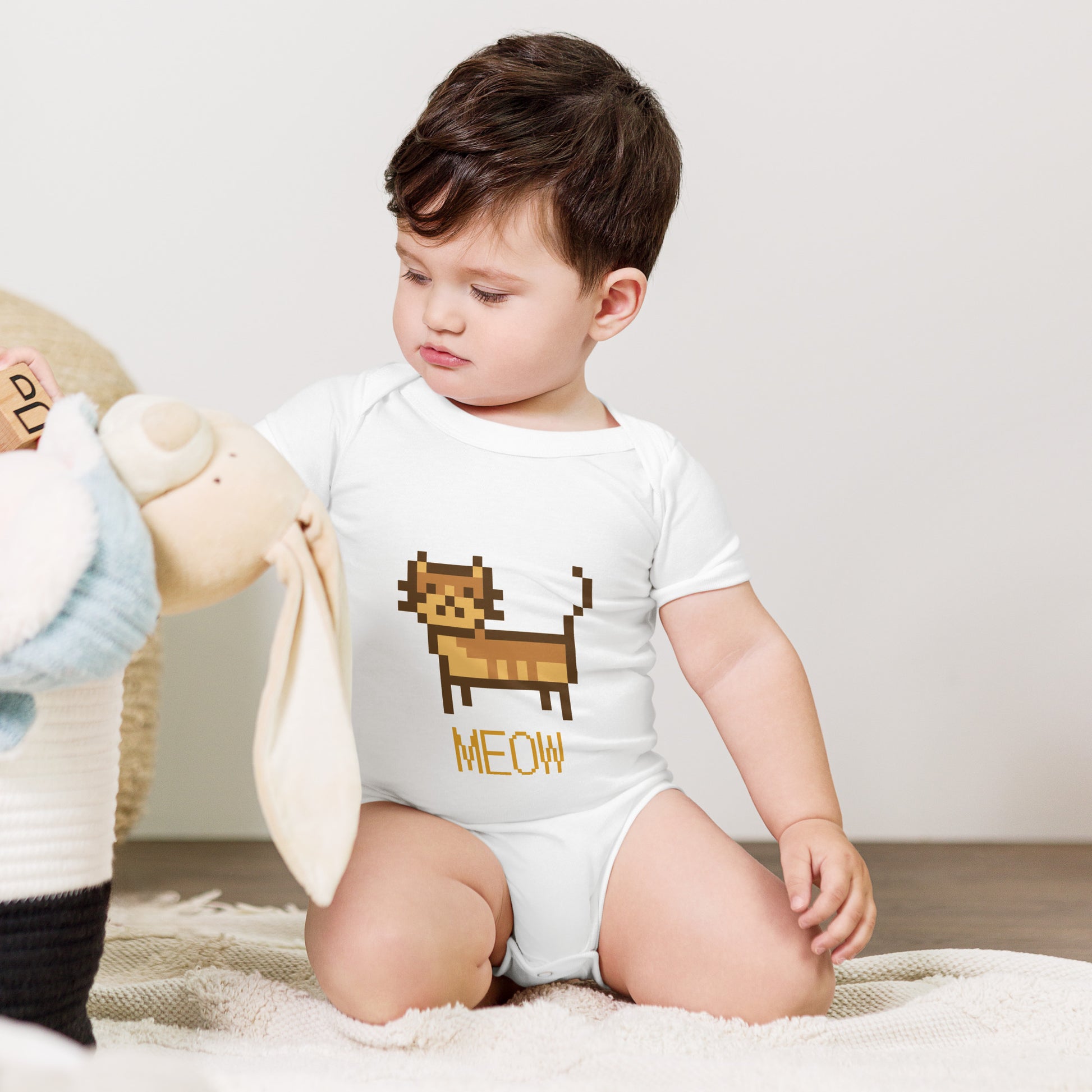 Baby with white short sleeve one piece with a pixeled picture of a cat and the text MEOW