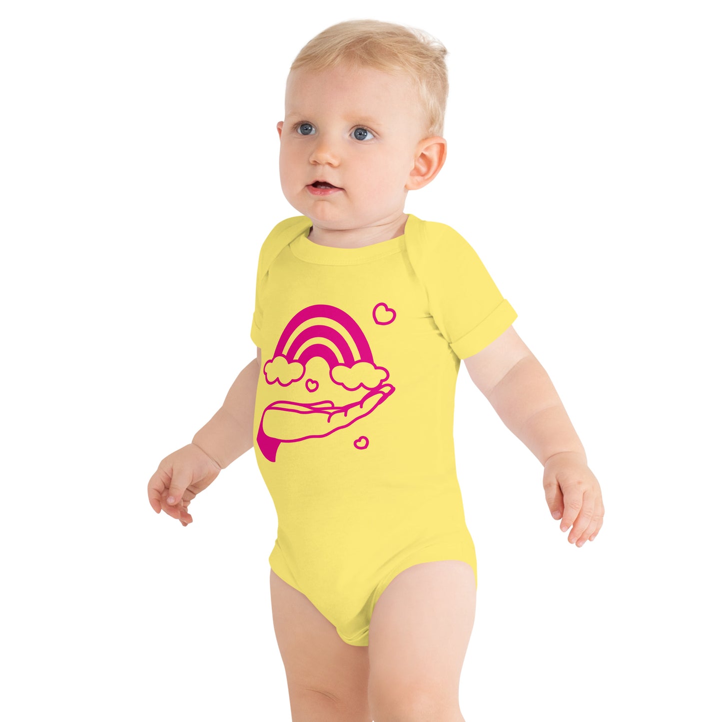 baby with yellow short sleeve one piece with print of pink hand holding a pink rainbow