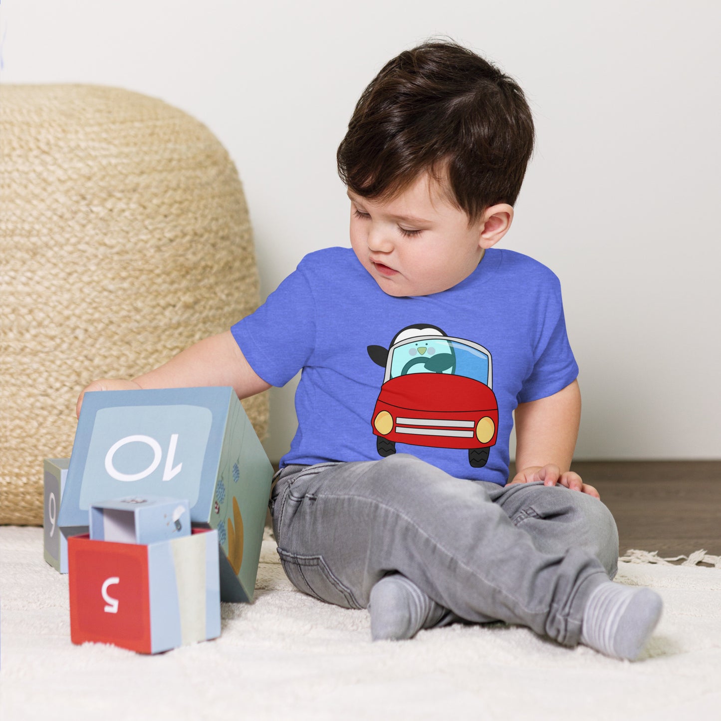toddler with blue t-shirt with picture of penguin driving a red car