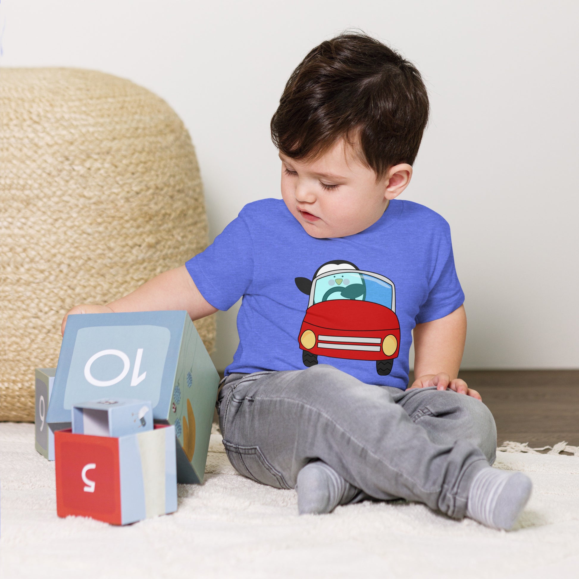 toddler with blue t-shirt with picture of penguin driving a red car