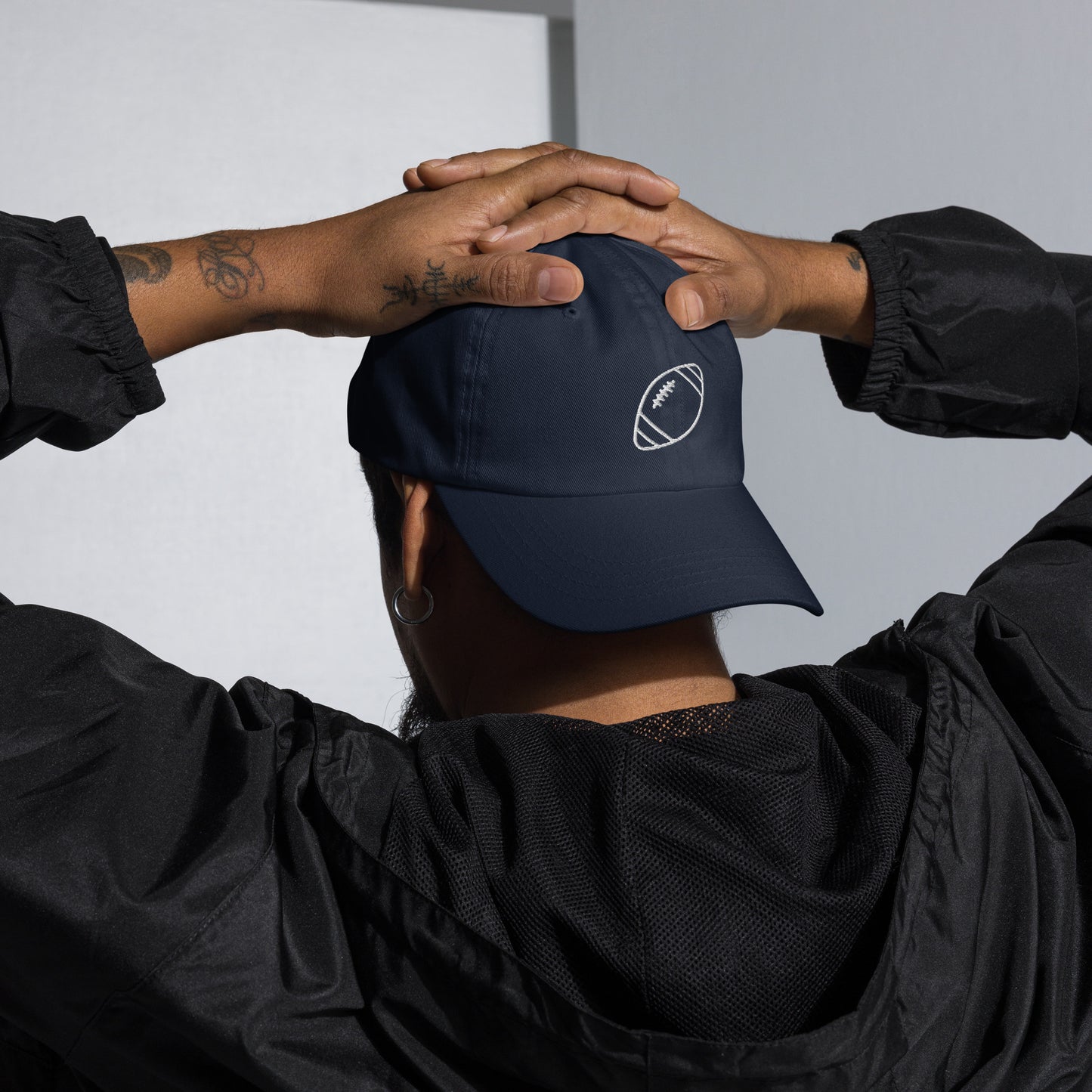 men with navy baseball cap with football
