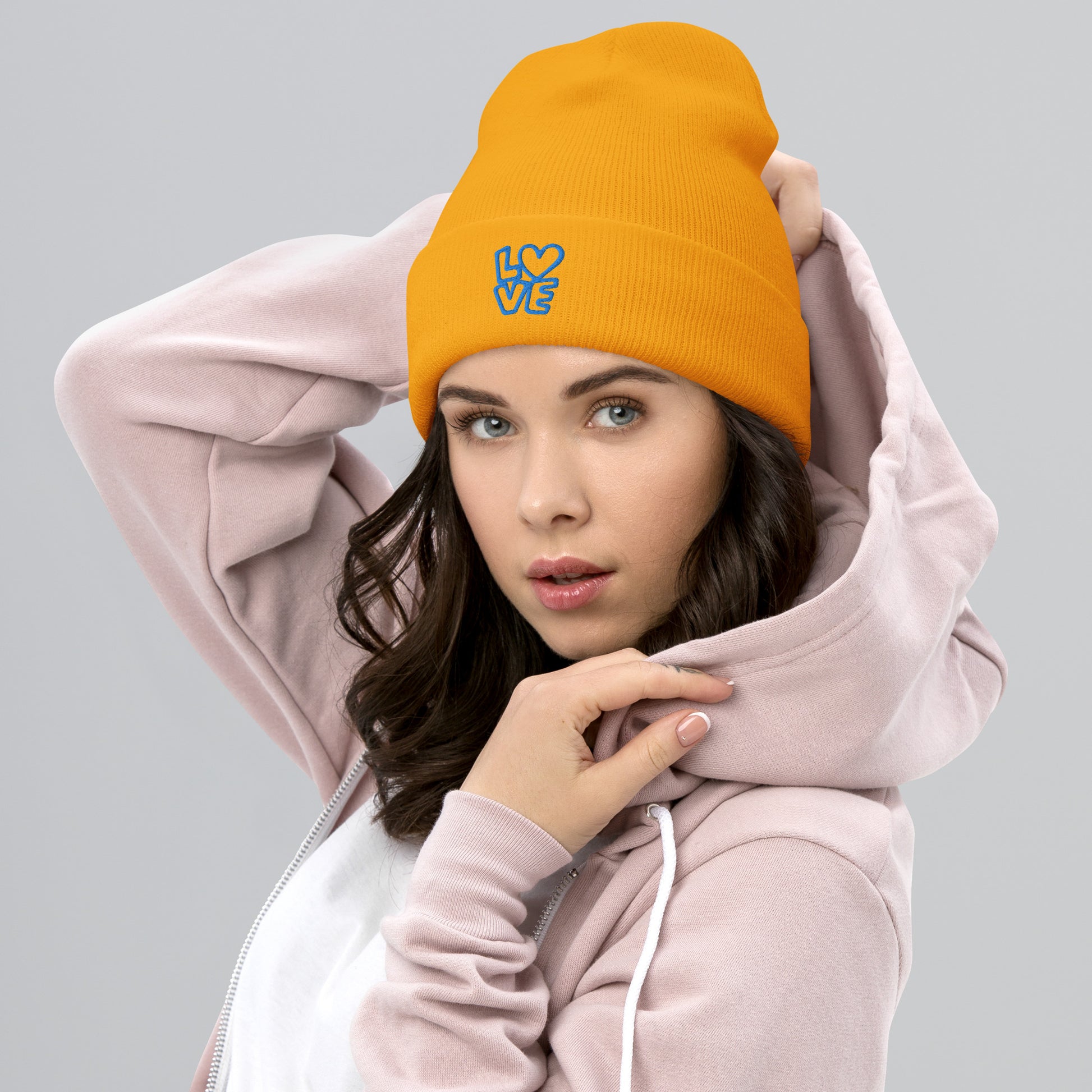 Women with yellow gold beanie with the blue letters LOVE with the O in heart shape