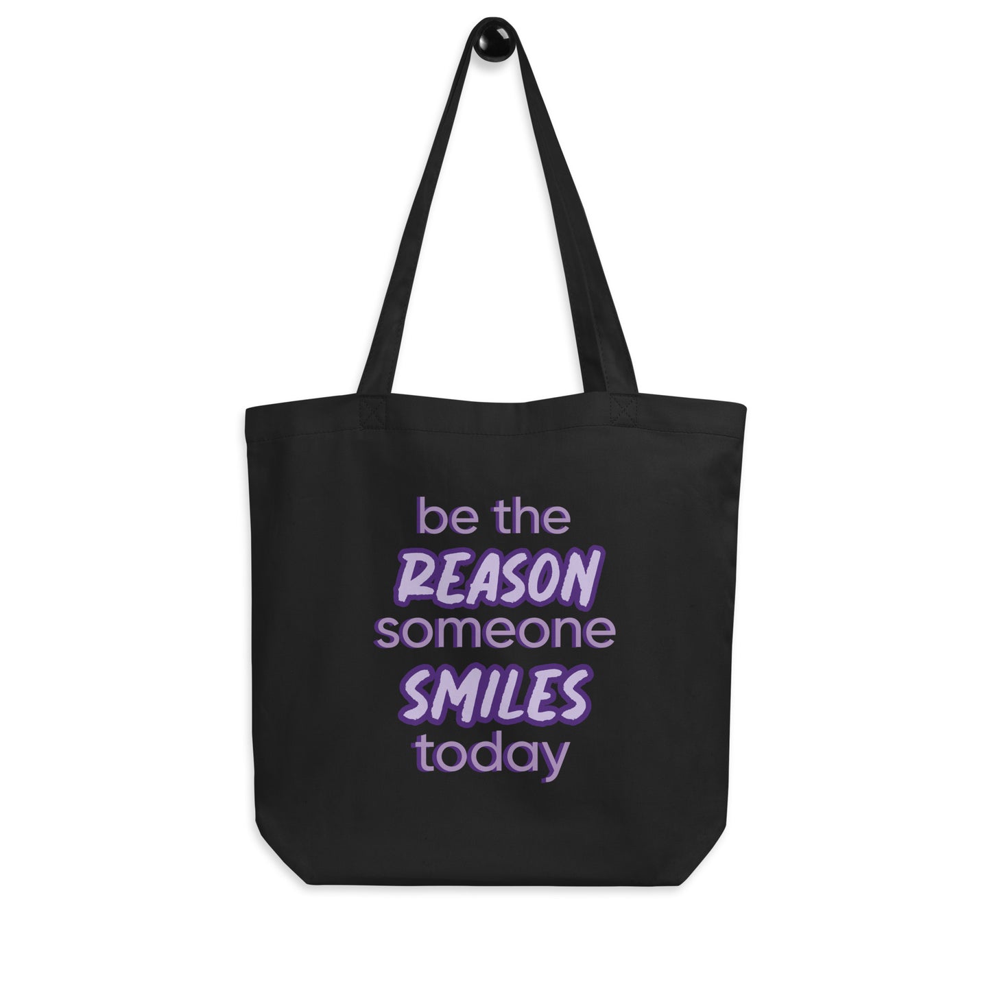 Black tote bag with the quote "be the reason someone smiles today" in purple on it.