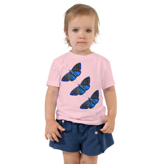 toddler with pink t-shirt with print of 3 blue butterfly's  