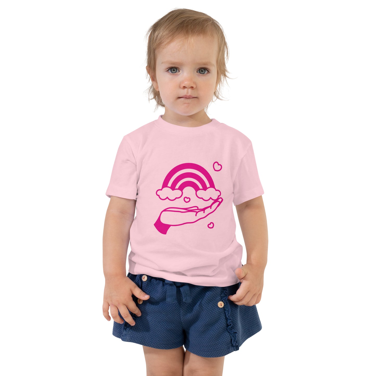 toddler with pink t-shirt with print of pink hand holding a pink rainbow