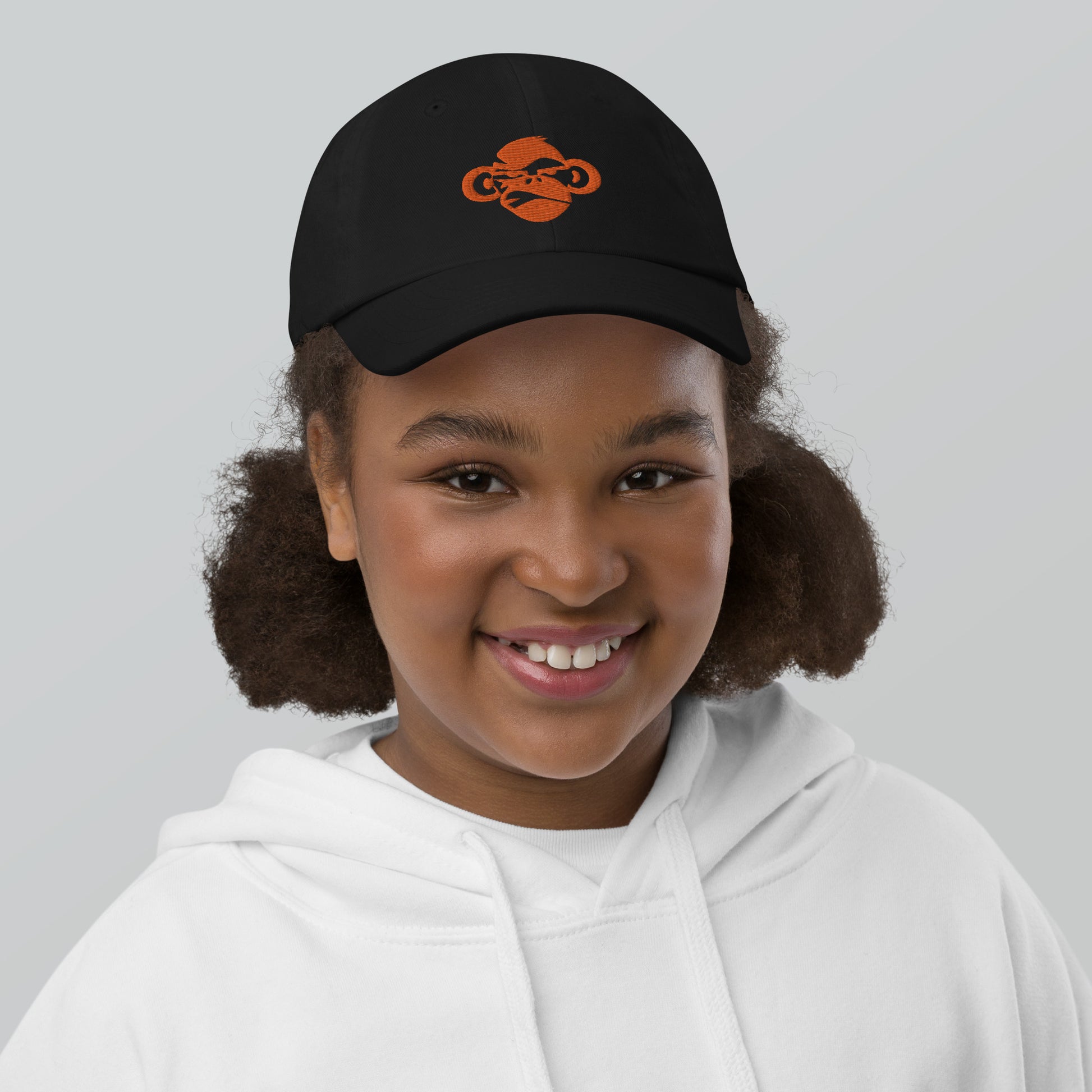 Youth with black baseball cap with a print of a head of a monkey in color brown