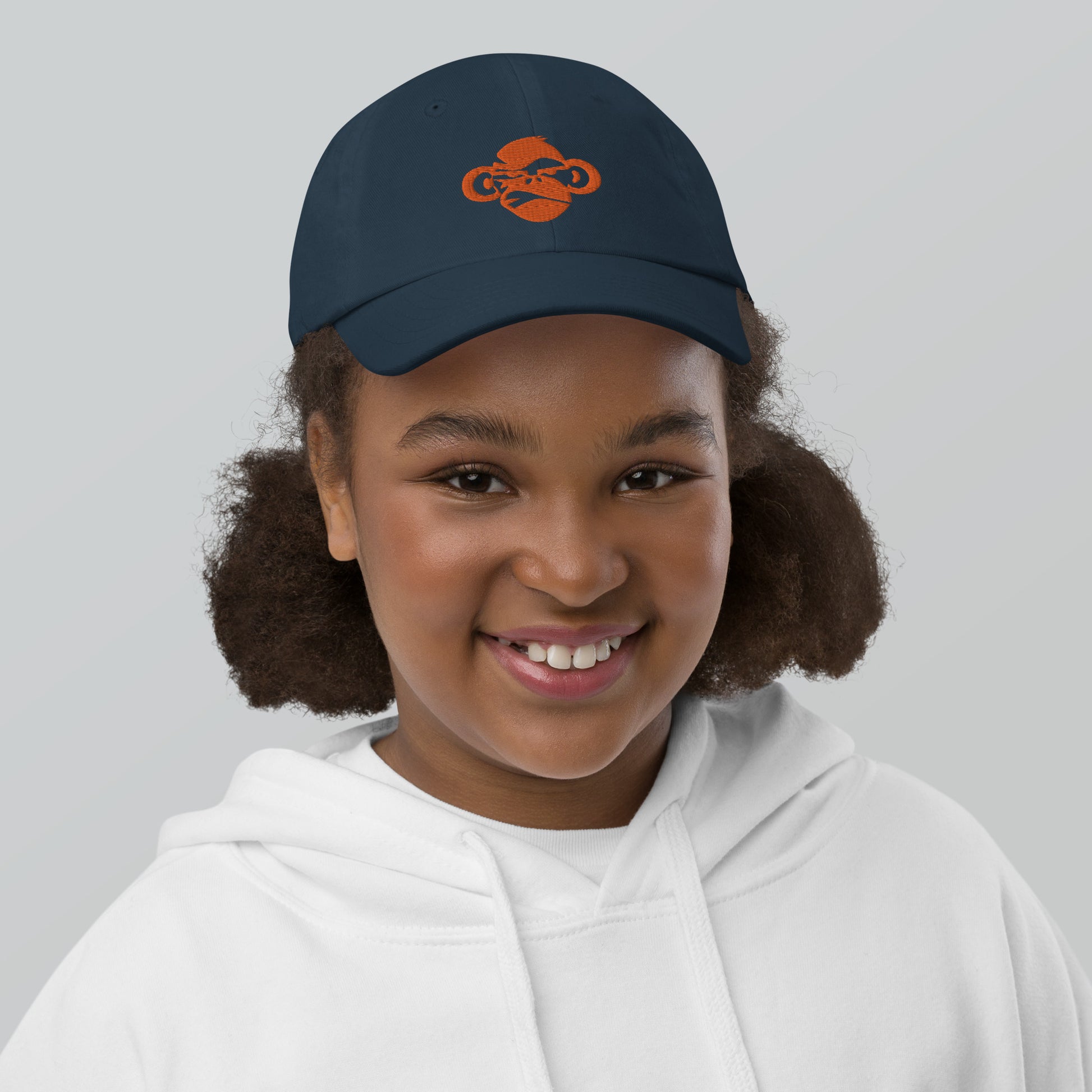 Youth with navy baseball cap with a print of a head of a monkey in color brown